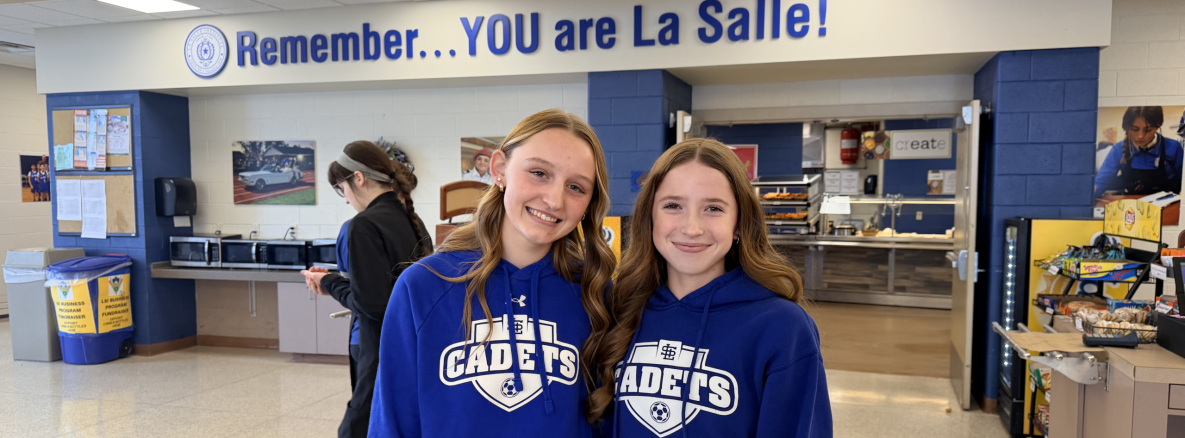 Two student standing under the sign "Remember.. You are lasalle!"
